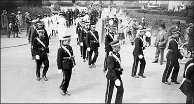 Members of St John Ambulance Brigade marching out of South Avenue into Station Road with members of the Fire Brigade following. c1925