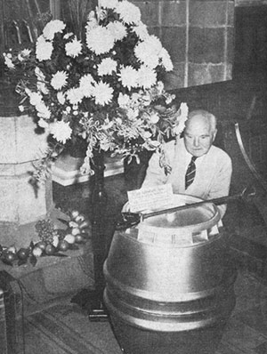 Photograph of Mr A V Morley with a display by Alumasc of a beer barrel and shootiing stick