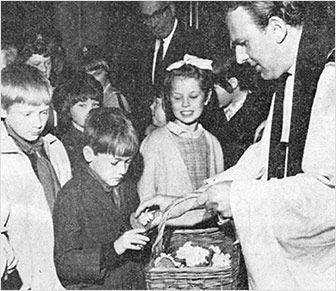 Photograph of Revd Derek Hole distributing primroses Mothering Sunday 1968 with Mr J R Loake (churchwarden) in the background