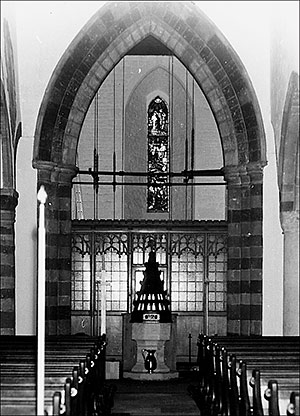 Photograph of church interior view to the west showing font and stained glass window