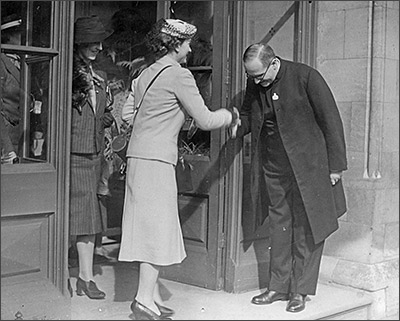 The Duchess of Gloucester visits the WVS in 1939 and is welcomed by the Revd Sharpley