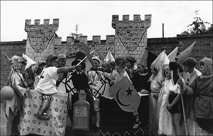 A group of children dressed in pantomime costumes pose in the playground in the early 1950s