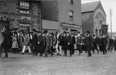 A parade in the early 1900s passes the Gas Company offices (far right)