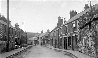 Another view of the High Street with the family home in the right foreground and the communal pump shown opposite.