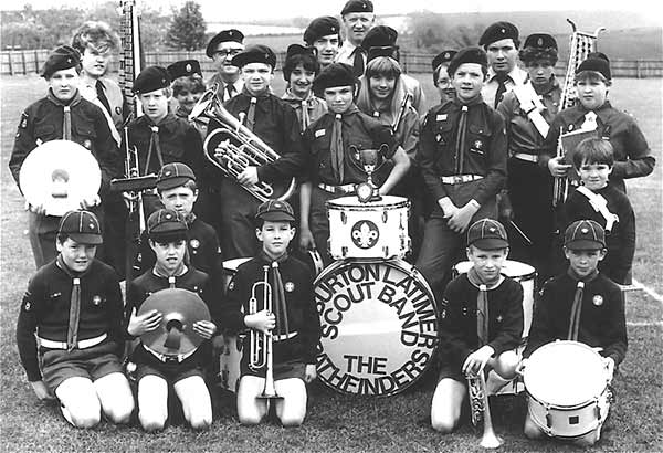 The Marching Pathfinders 1984. At back, Les Facer. Back Row - Lisa Wright, Jack Addis, Nicky Billiington, David Billington and Mick Clarke. Next row - Amanda Roe, Amanda Abrams, ? Abrams, Sarah Skelly and Barbara Facer. Next row - Kevin Lington, Chris Banks, Andrew Hancock, Simon Loak, Andrew McGeorge and Sandra Facer. Kneeling - Paul Hughes, Stewart Rae (Thomas Skelly behind him), Richard Lington, Gareth Noble, the mascot Mathew Clarke (standing) and Ian Griffiths.