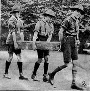 Scouts carrying log helping at a fete