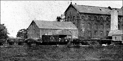 Photograph showing Midland Railway trucks standing in front of the mill together with the Shire horse that pulled the wagons on to the site.  The tall building in the background is still at the heart of the modern-day mill complex.