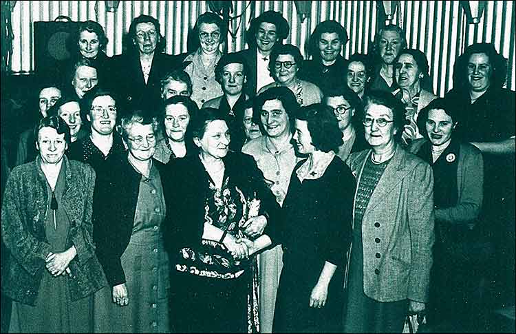 British Legion Ladies thank Mrs Barlow c1950s.  Roma Thorne presents a gift to Mrs Barlow, outgoing President of Burton Latimer Ladies Section.  Back Row: ?, Mrs Mason, Mrs Phillips, Mrs Gaskin, Mrs Darnell, Mrs Walker.  Second Row: ?. ?, Mrs Spenjce, Mrs Wells, ?, Eva Elliott.   Third Row: ?, Mrs Barber, Mrs Crick, ?, ?, Mrs Stokes, Mrs Doris Brace, Millie Reed.  Front Row: Mrs Annie Brace, Mrs Cox, Mrs Barlow, Roma Thorne, Mrs Clarke